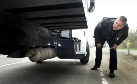 A DOT Officer inspecting vehicle maintenance defects on a truck