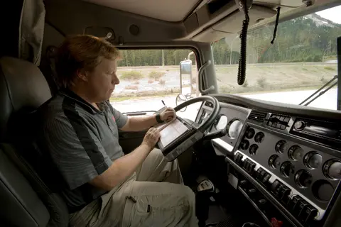A truck driver filling out a logbook in need of an ELD